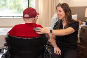 Smiling nurse at Hilltop Park listening to patient's breathing with stethoscope